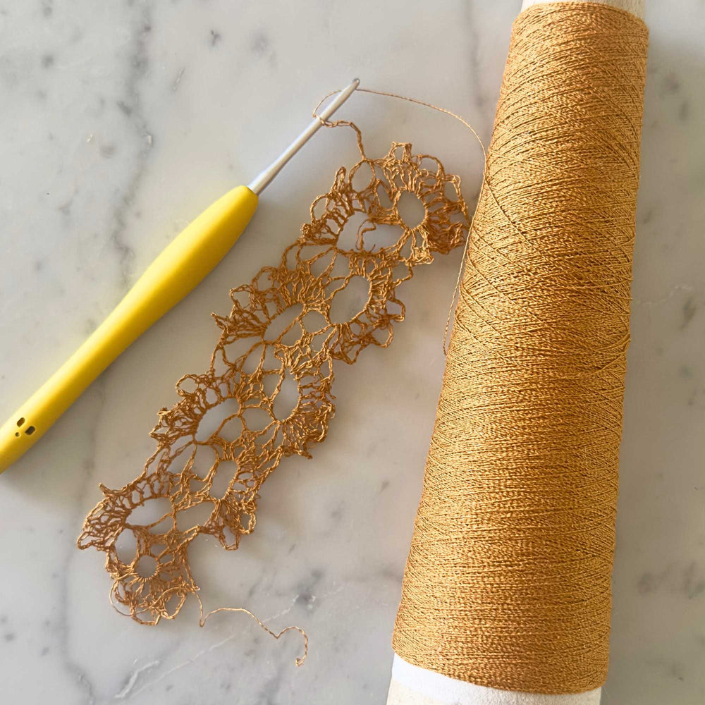 crochet work in progress using habu textiles silk stainless steel in yamabuki orange. pattern is the queen anne lace scarf - repurposing for a necklace