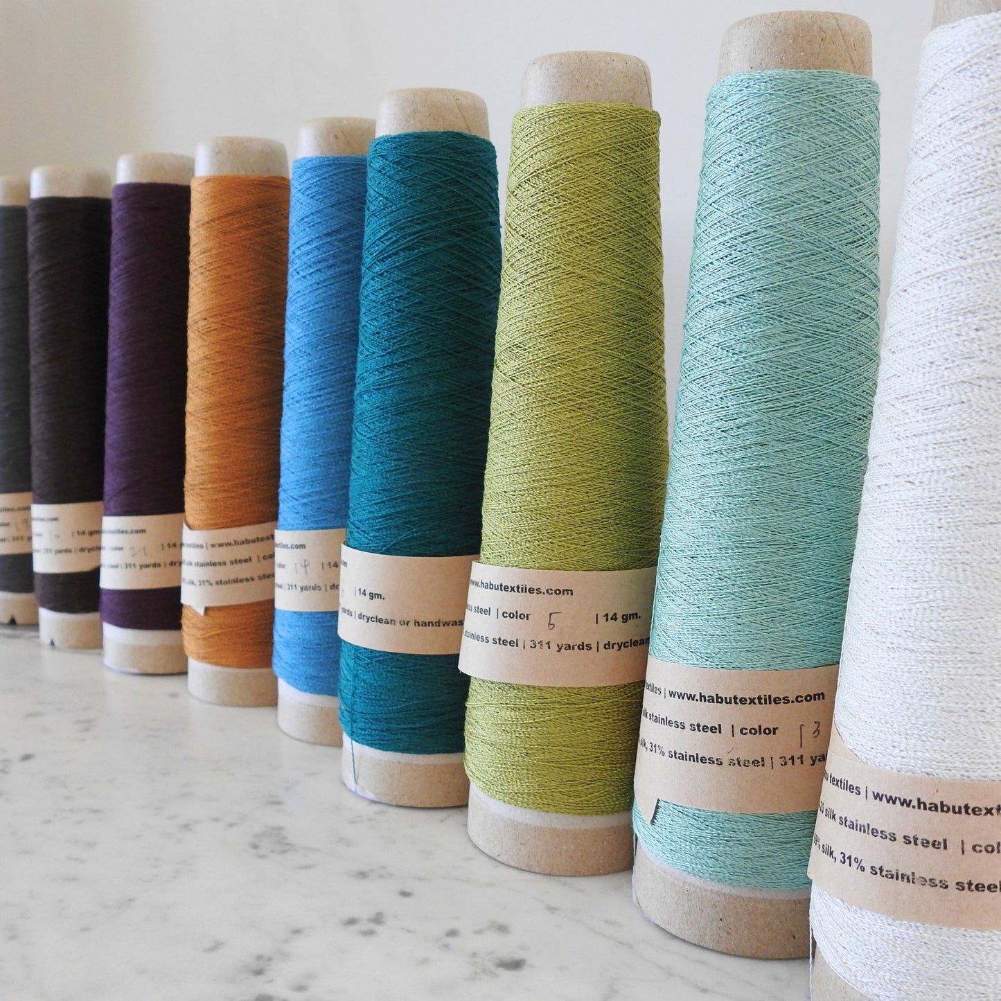 
                  
                    Cones of Silk Stainless Steel lace weight yarn  for knitting crochet and weaving. Make beautiful scarves, garments and jewelry. The yarn has a stainless steel core with fine silk wrapped around it. They cone of yarn has a very elegant sheen and is beautiful to look at. Habu Textiles A20
                  
                