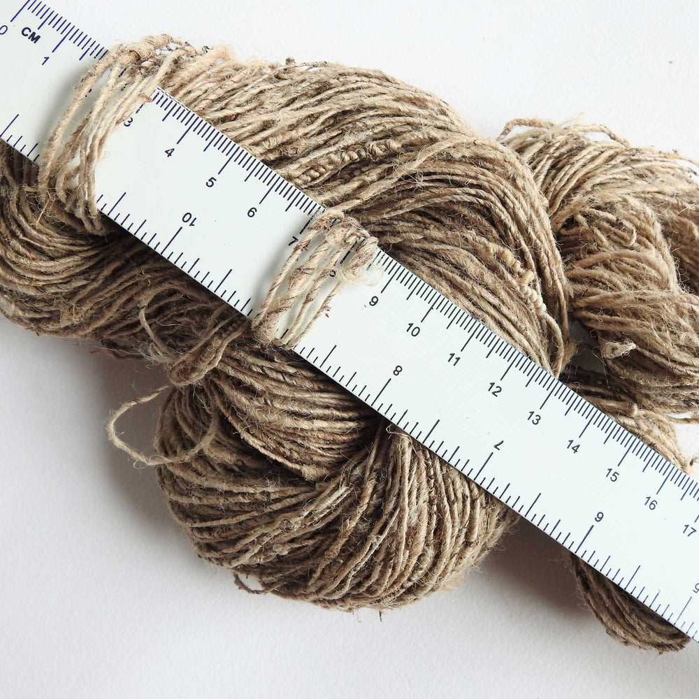 
                  
                    A skein of Nettle yarn resting against a tape measure to show thickness of the yarn. Nettle is a highly sustainable and eco friendly crop. ORA Fabulous Fibres Nettle yarn is hand spun with a beautiful thick and thin texture giving it a rustic finish. Nettle yarn is available in a range of colours.
                  
                