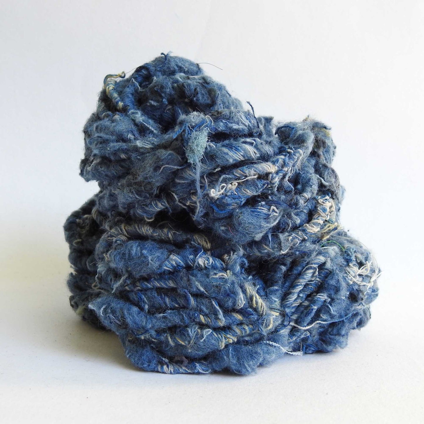 a hank of recycled denim yarn. our recycled denim is handspun with loads of texture. hand crafted from repurposed denim jeans. soft and chunky yarn for weaving, knitting, crochet