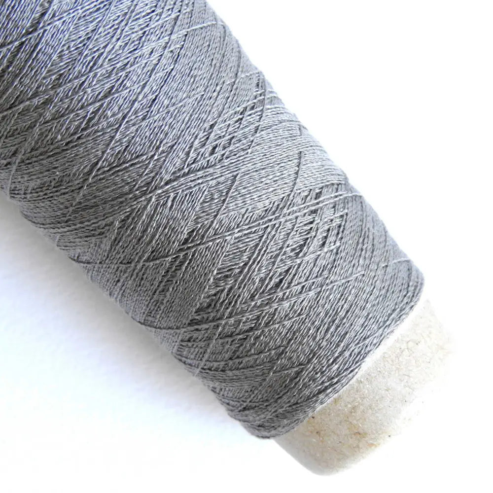 
                  
                    A cone of Silk Stainless Steel lace weight yarn in Top Gray for knitting crochet and weaving. Make beautiful scarves, garments and jewelry. The yarn has a stainless steel core with fine silk wrapped around it. They cone of yarn has a very elegant sheen and is beautiful to look at. Habu Textiles A20
                  
                