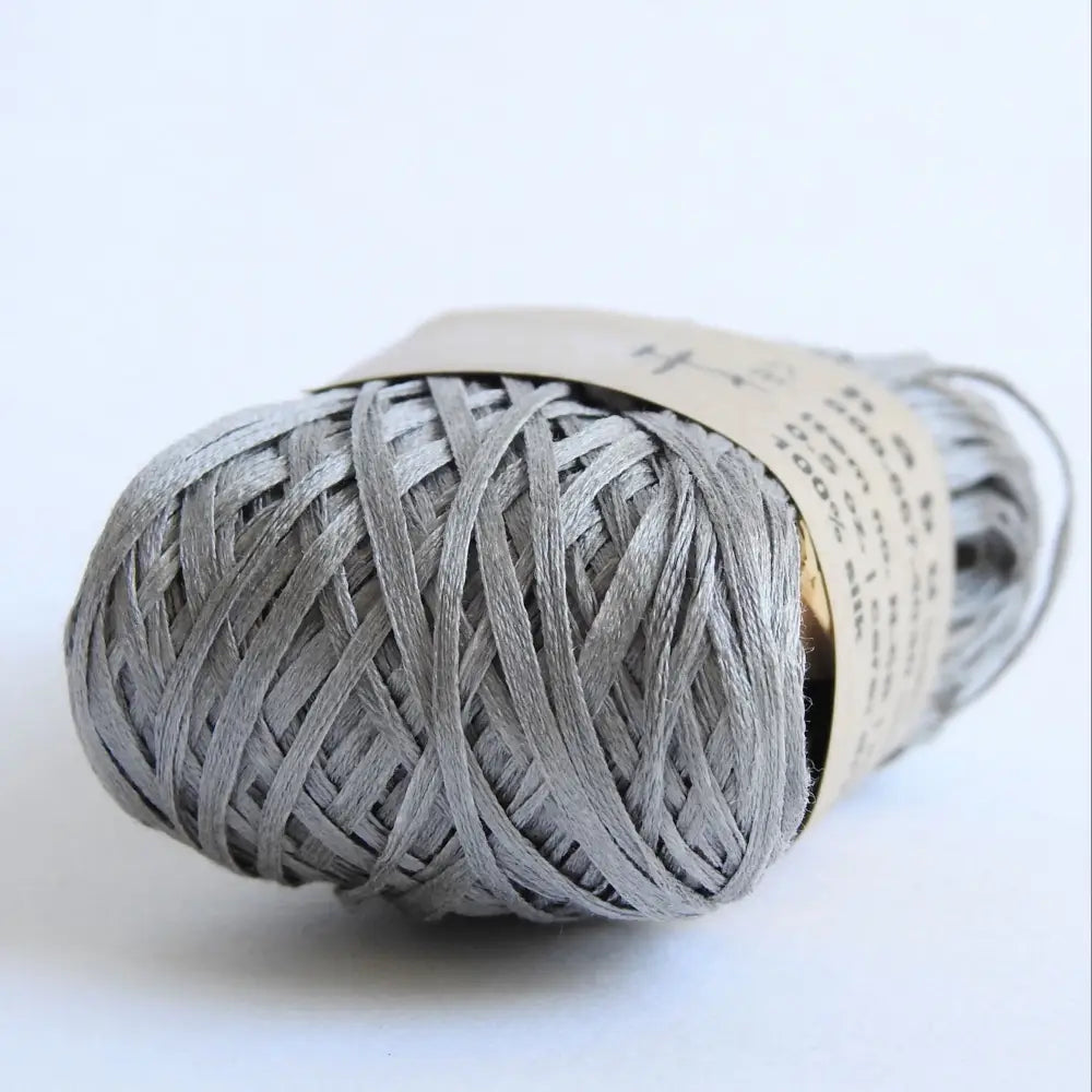 
                  
                    Ball of Habu Silk Tape Yarn in Gray. 100% Japanese silk yarn for knitting, crochet, weaving. Make hats, bags, garments, shawls. Silky and luminous fine tape. Habu Textiles N-6B
                  
                