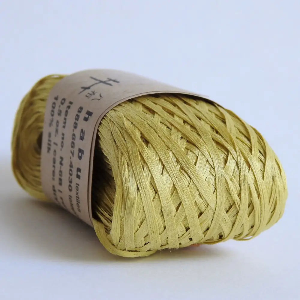 
                  
                    Ball of Habu Silk Tape Yarn in Mustard. 100% Japanese silk yarn for knitting, crochet, weaving. Make hats, bags, garments, shawls. Silky and luminous fine tape. Habu Textiles N-6B
                  
                